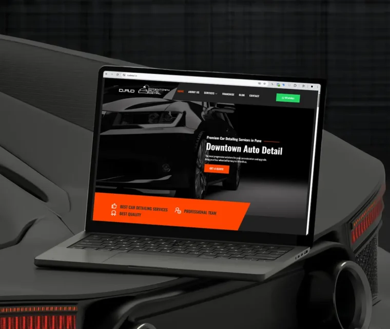 Laptop displaying the Downtown Auto Detail website, a car detailing service in Pune, designed by Thinkster — featuring a sleek black and orange interface with bold typography and a premium automotive aesthetic.