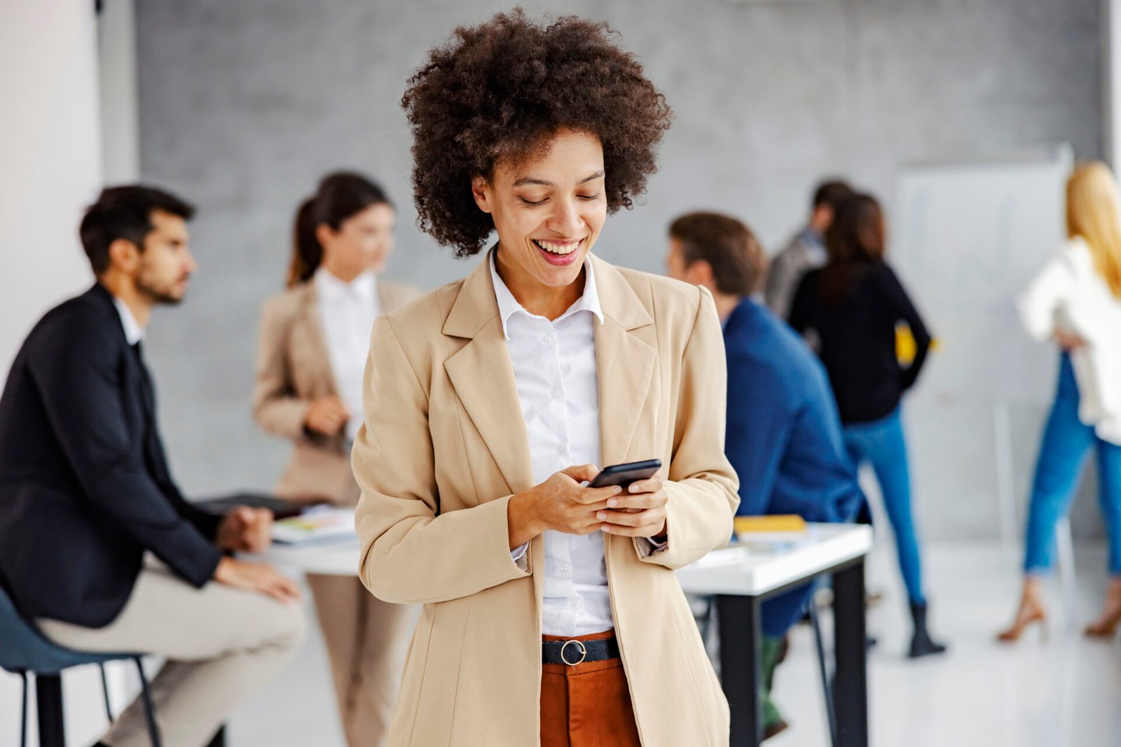 A smiling mixed race businesswoman typing messages on the phone at the office.