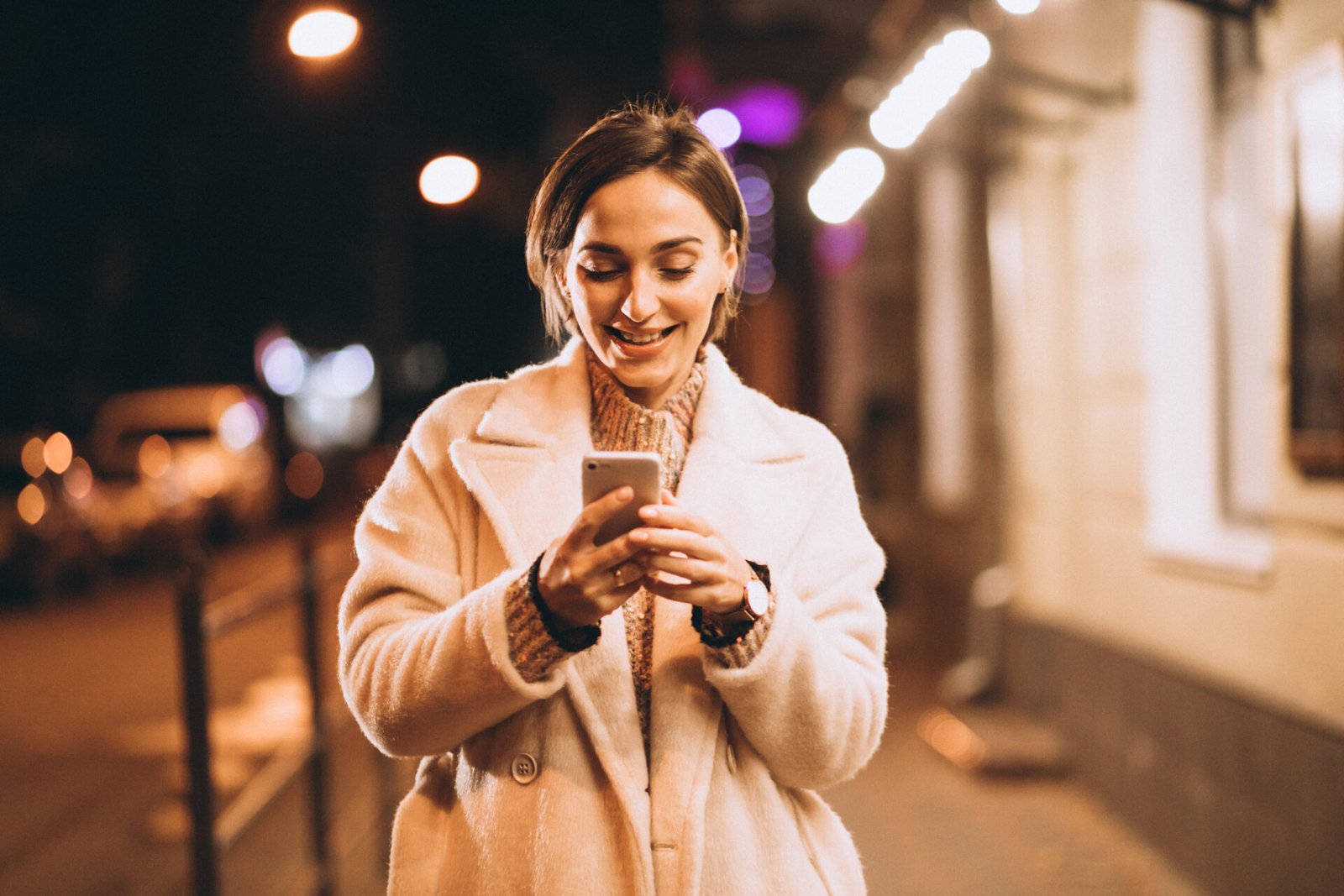 Young woman using phone outside the night street